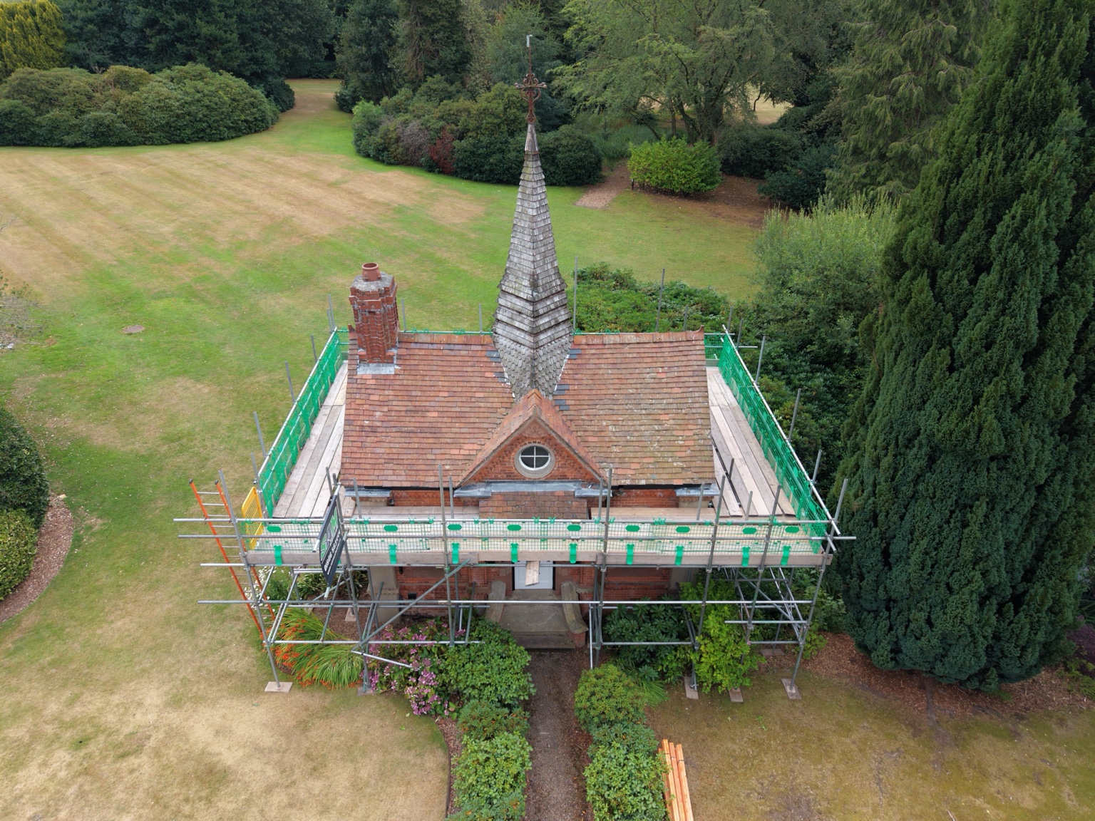 Front view of Bostock Hall boathouse showing its spire, circular window and boarded scaffold platforms
